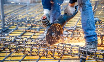 construction industry details - worker cutting steel bars using angle grinder mitre saw.